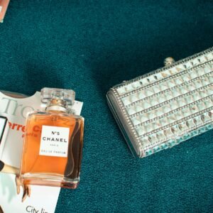 A luxurious setup featuring Chanel No.5 perfume beside a stylish silver clutch.